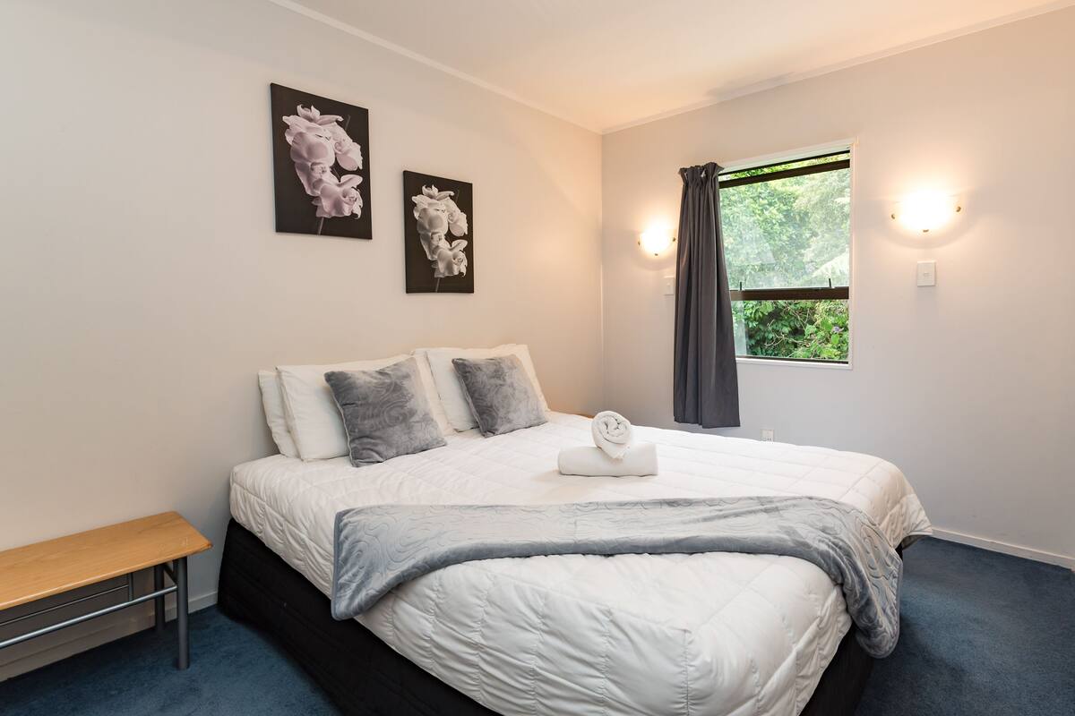 A bedroom with a bed, a bench, and two wall-mounted light fixtures.