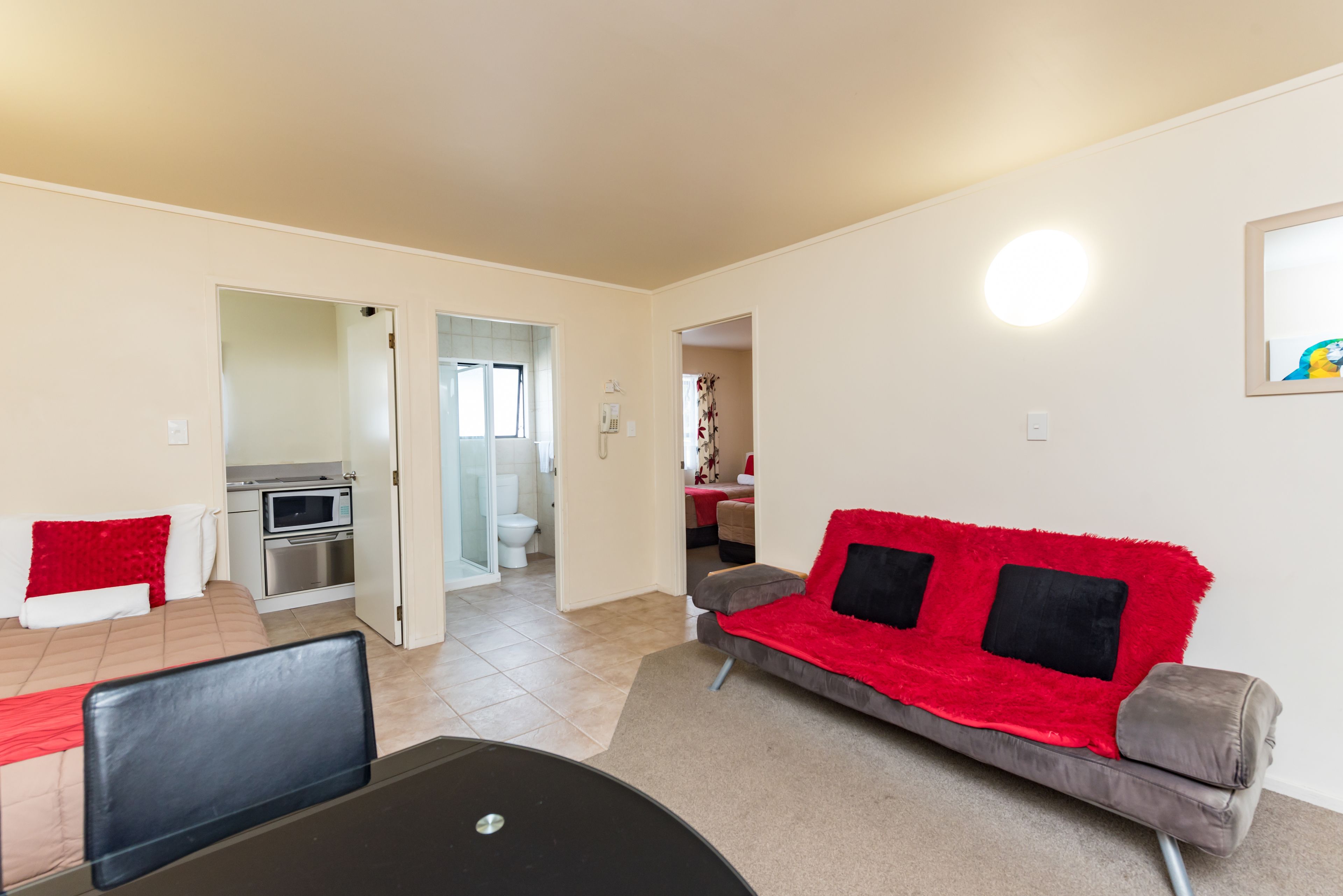 A living room with a sofa, a dining table, and a kitchen area visible through an open door.