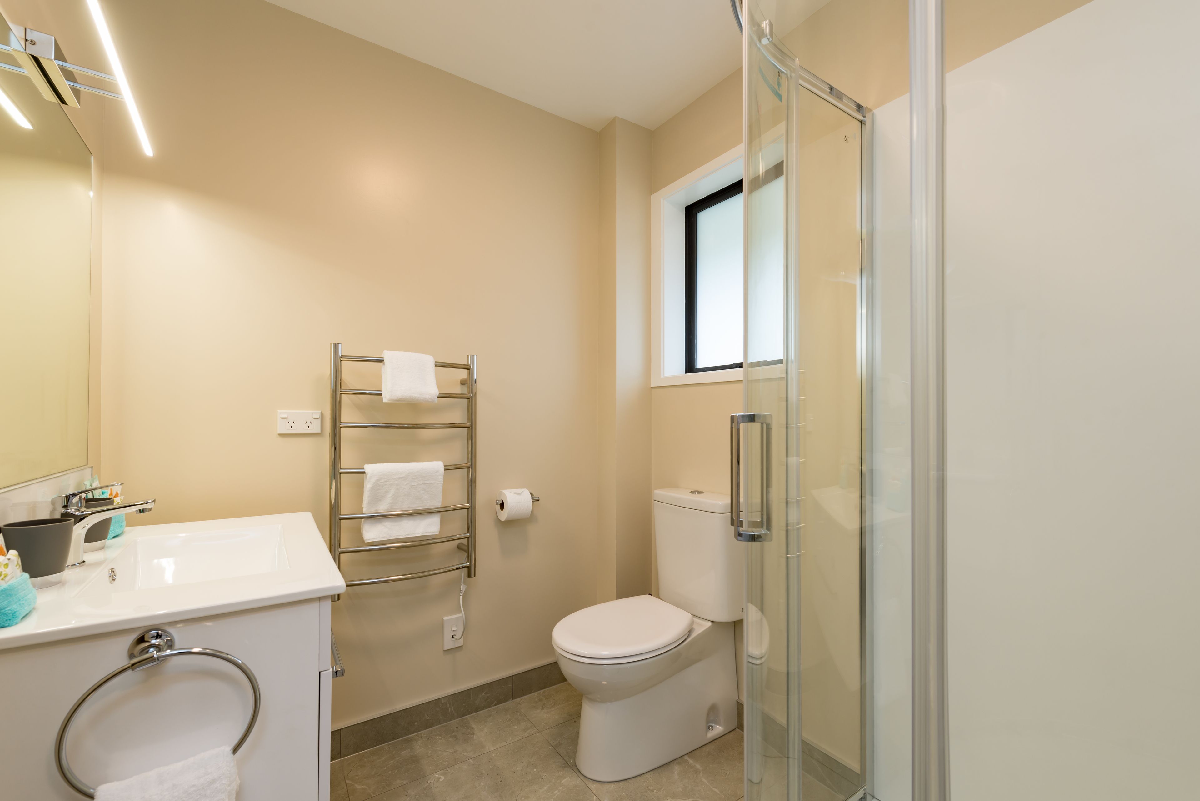 A modern bathroom with a glass shower enclosure, a white sink, and a toilet.