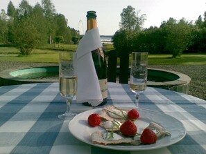 A table set with a bottle of champagne, two glasses, and a plate with strawberries and cream. - Sikfors Herrgård (Hallefors)