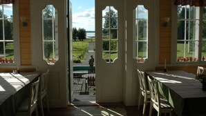 A room with a view of a garden and a body of water through large windows. - Sikfors Herrgård (Hallefors)