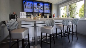 A bar area with a counter, bar stools, and shelves of bottles and glasses. - Hotel Am Freischuetz (Huerth)
