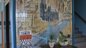 A tiled mural depicting a cityscape with a bridge, a castle, and a river. - Hotel Am Freischuetz (Huerth)