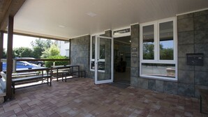 A hotel entrance with a glass door, outdoor seating, and a view of the street. - Hotel Am Freischuetz (Huerth)