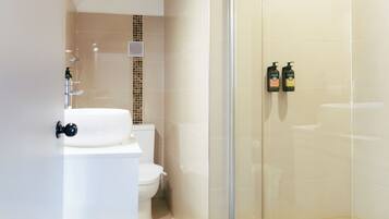 A modern bathroom with a glass shower enclosure, a white sink, and a toilet.