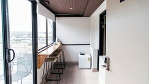 Una cocina moderna con encimera de madera, taburetes de bar, un refrigerador y una ventana con vistas a la ciudad.