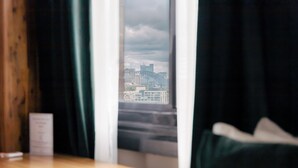 Habitación de hotel con vista a un horizonte urbano a través de una ventana con cortinas.