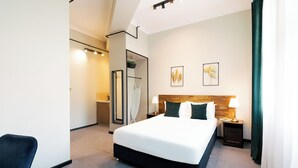 Una habitación de hotel moderna con una cama grande, un escritorio, una silla y un espejo.