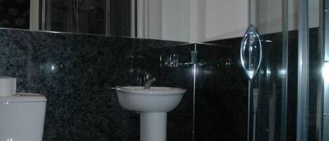 Un baño moderno con inodoro, lavamanos y ducha.