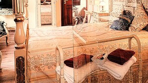 A four-poster bed with a dark red throw blanket, a wooden headboard, and a floral-patterned bedspread. There is a nightstand with a lamp and a mirror. The room has ornate wall decorations and a wooden floor. - Hotel Denkmal 13 – Rostock (Rostock)