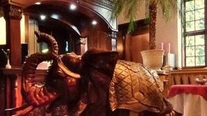 A room with a large elephant statue, a palm tree, and a table with a red tablecloth. - Hotel Denkmal 13 – Rostock (Rostock)