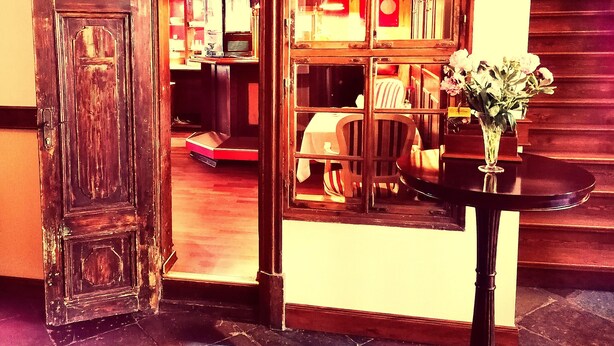 A room with a wooden door, a table with a vase, and a staircase. - Hotel Denkmal 13 – Rostock (Rostock)