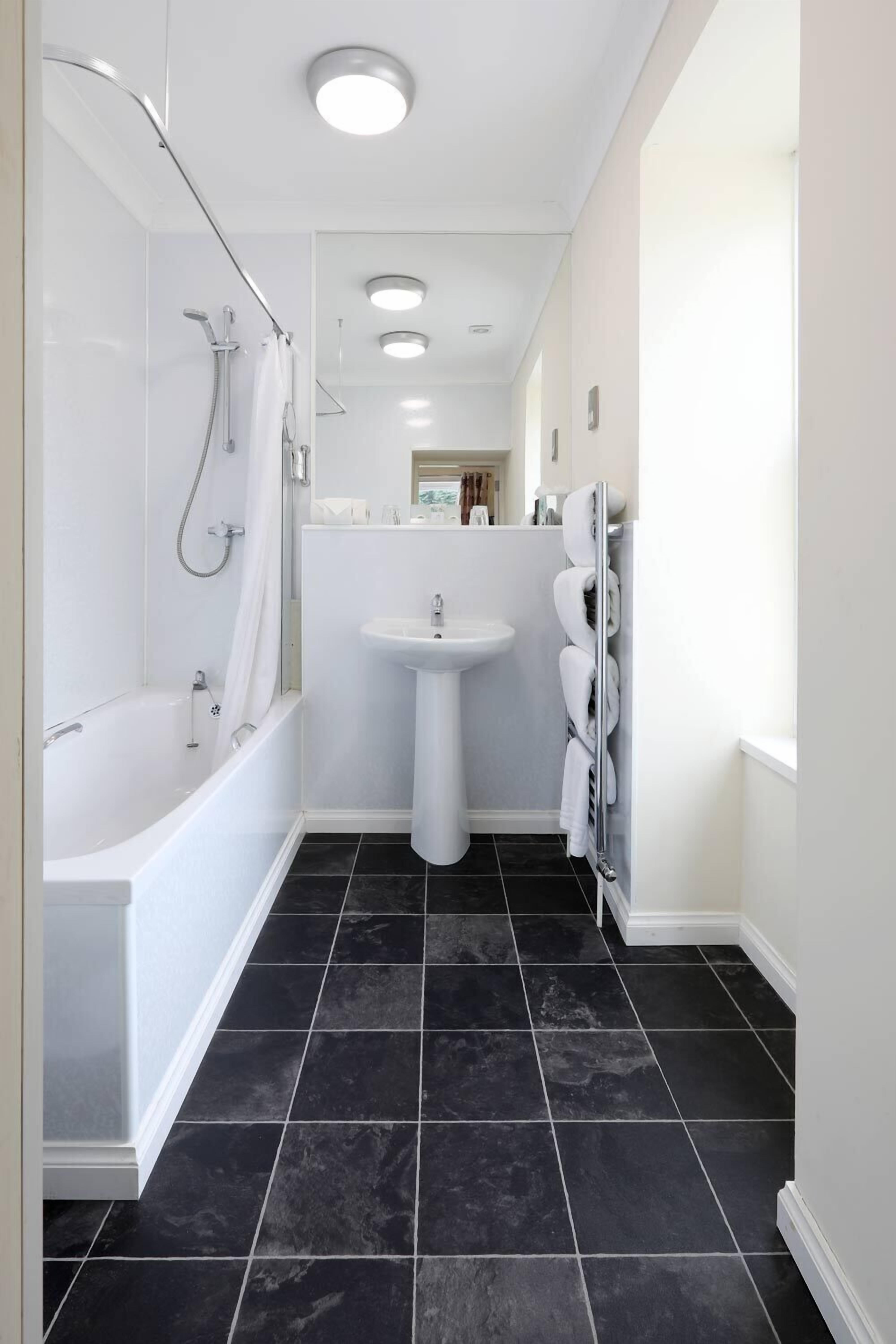 A modern bathroom with a bathtub, shower, and sink.