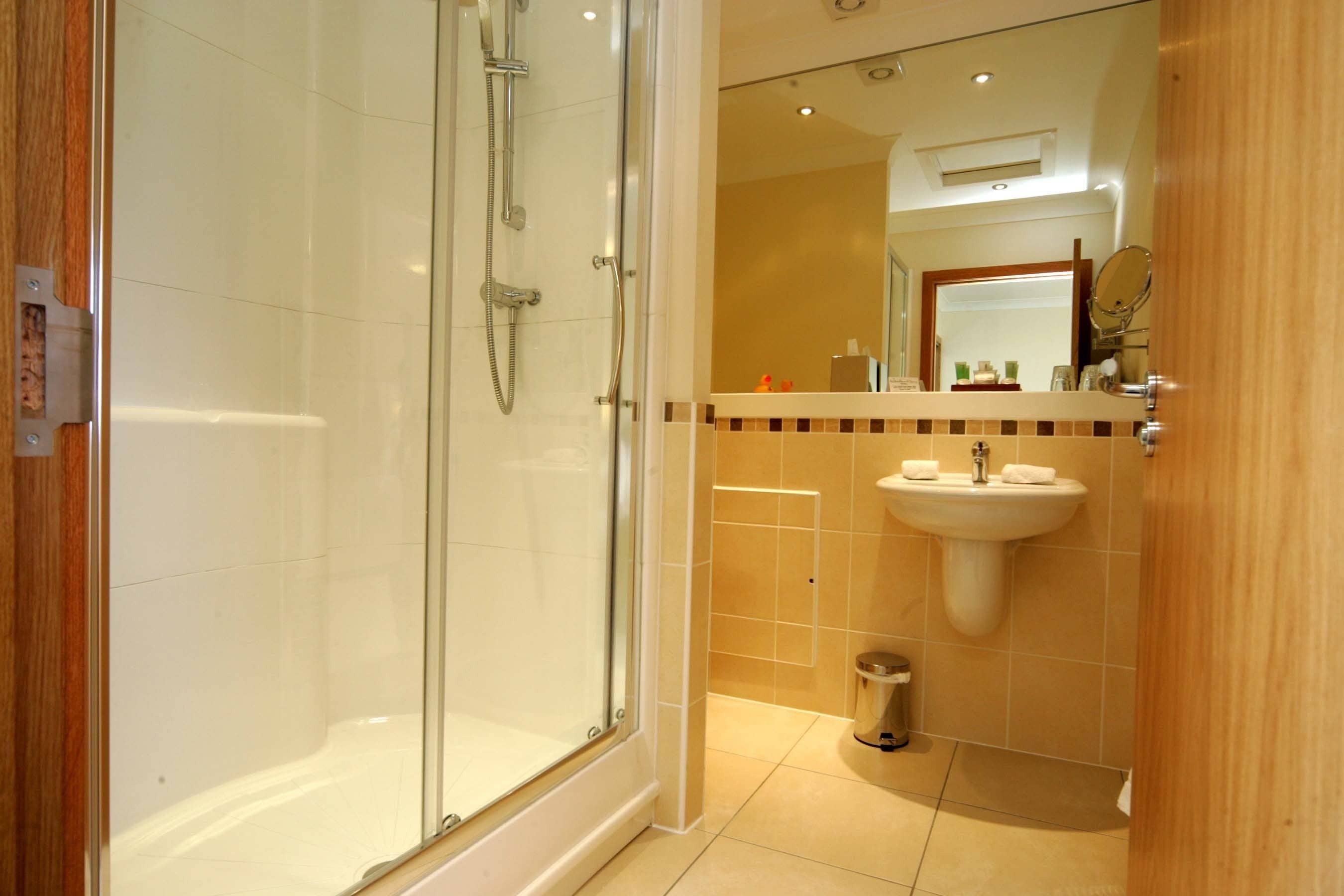 Een moderne badkamer met een douchecabine van glas, een wastafel en een spiegel.