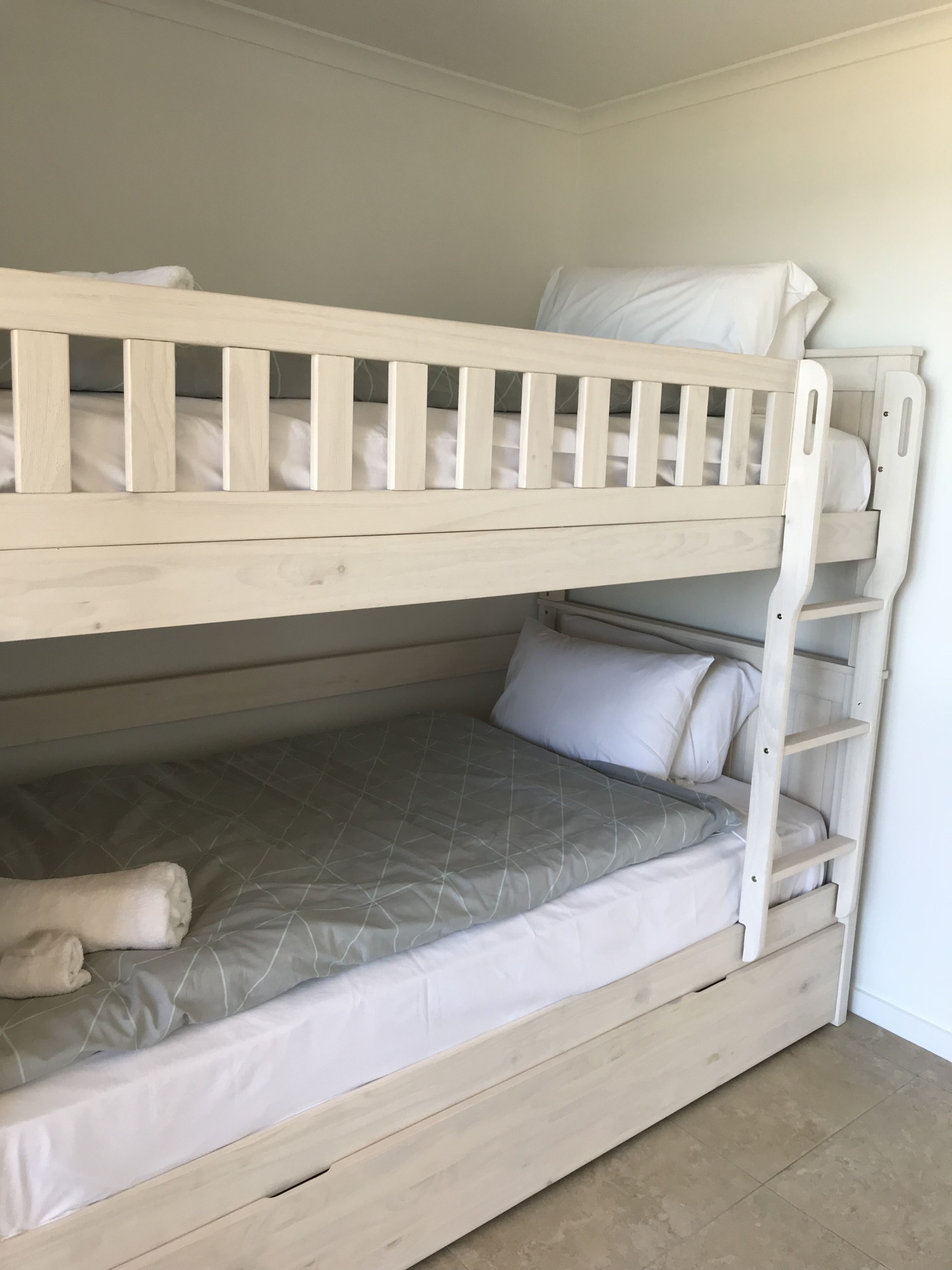 Una cama litera con escalera, colchón y almohadas.