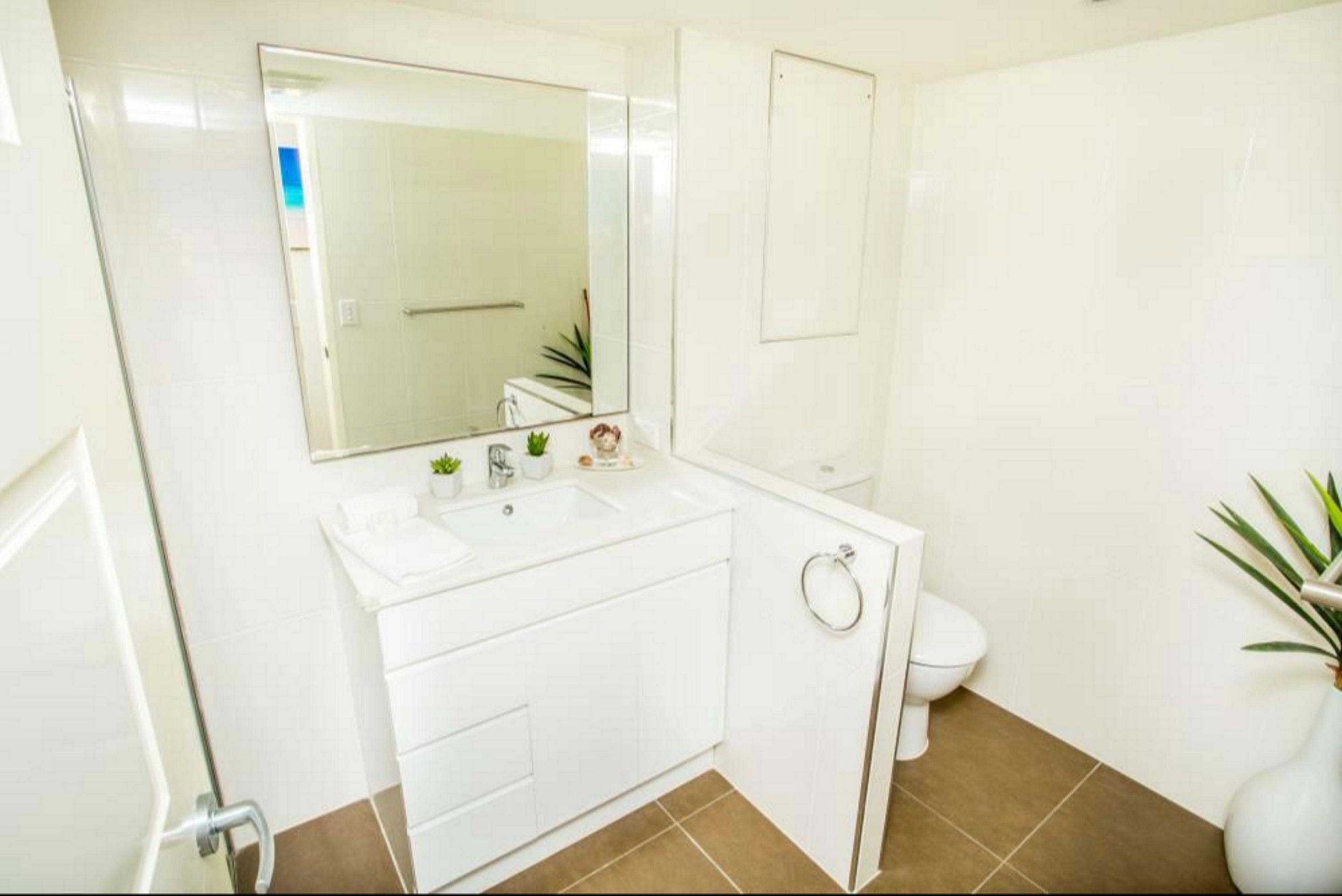 Une salle de bain moderne avec un lavabo blanc, un miroir et des toilettes.