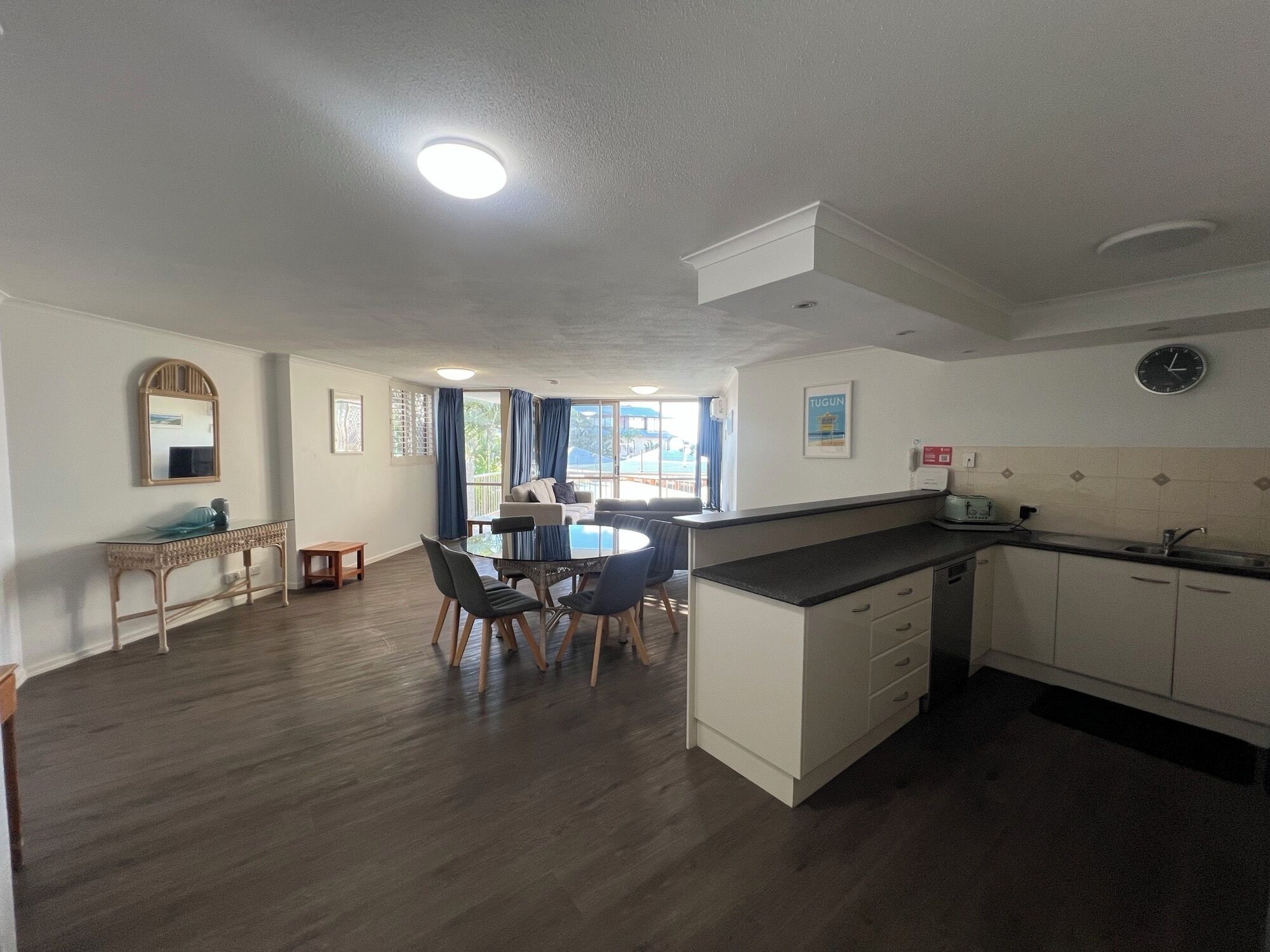 A hotel room with a dining area, a kitchen, and a large window with curtains.