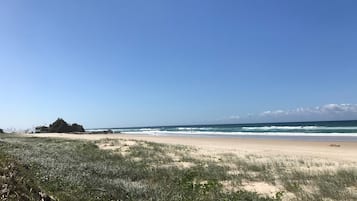 A beach with a rocky outcrop and waves.
