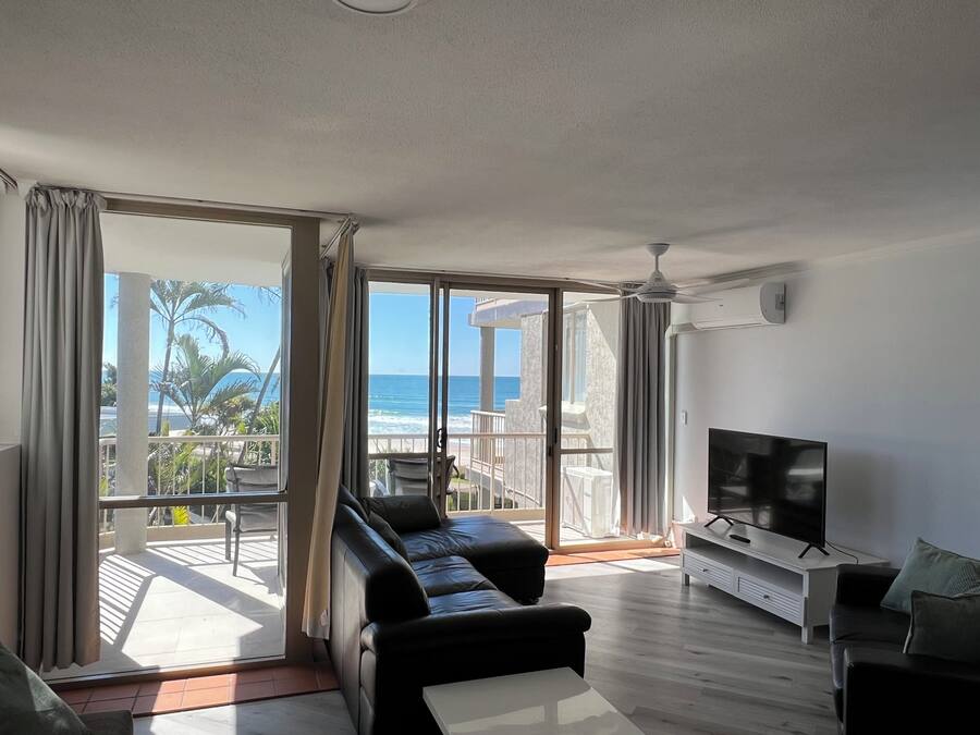 A modern living room with a large sliding glass door leading to a balcony with a view of the ocean.