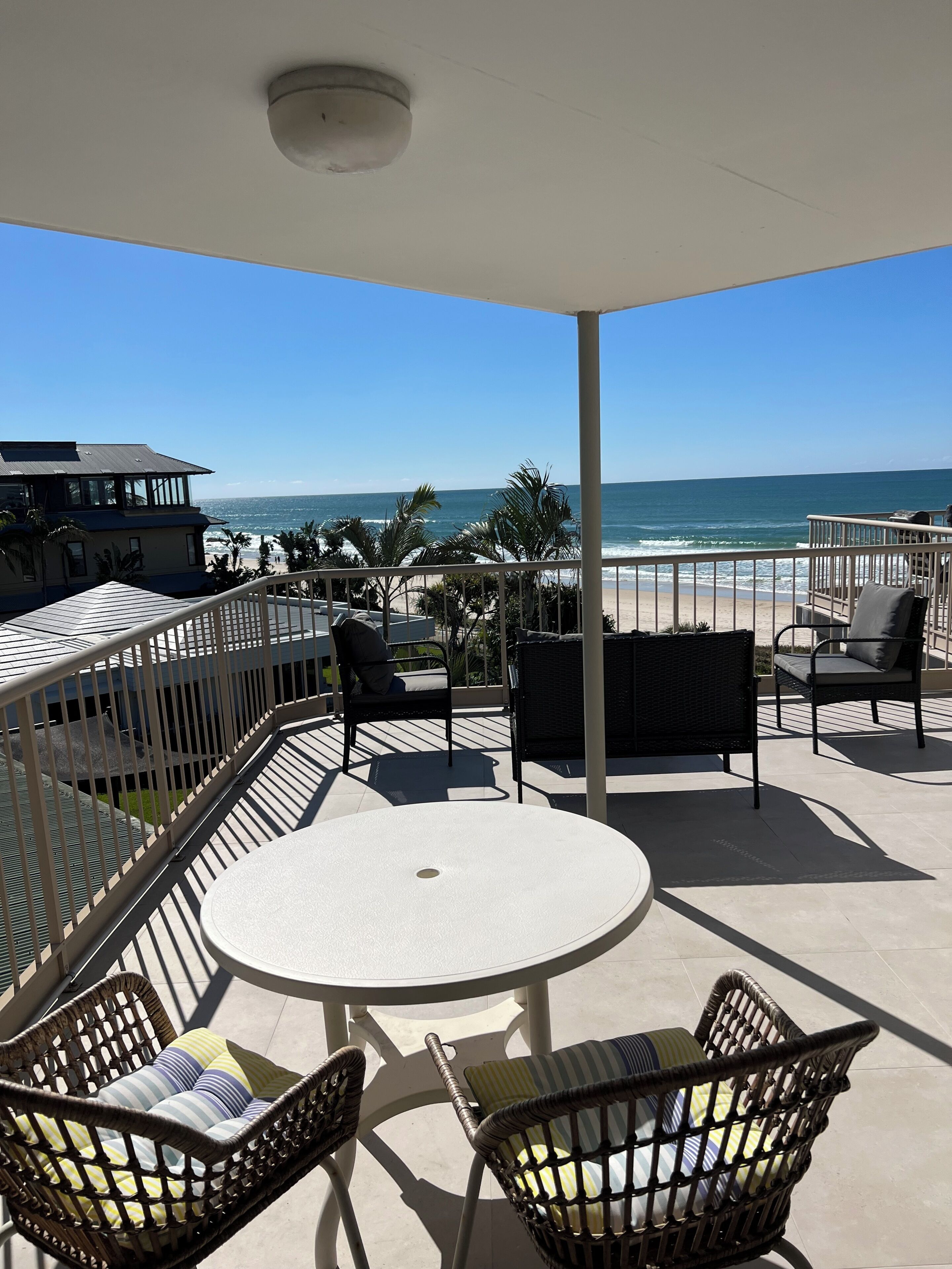 A covered outdoor seating area with a view of the beach and ocean.