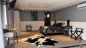 Un dormitorio moderno con cama, televisor de pantalla plana, alfombra de cuero de vaca y una mesita con una revista.