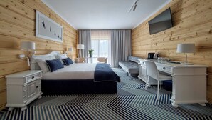 Una habitación de hotel con cama, escritorio y televisor.