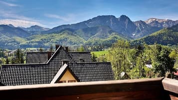 Vista de una montaña con una casa que tiene techo inclinado y terraza de madera.