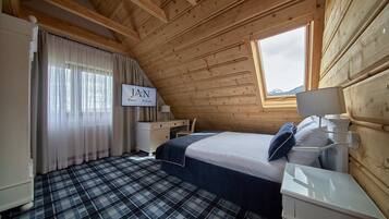 Une chambre avec un lit, un bureau et une fenêtre donnant sur les montagnes.
