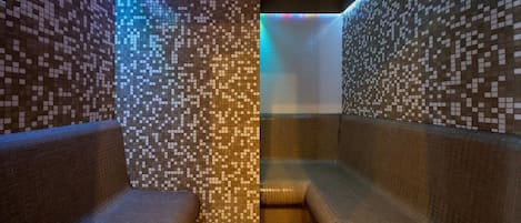 A tiled bathroom with benches and a tiled wall.