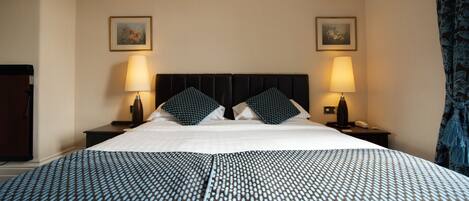 A hotel room with a large bed, two nightstands, two lamps, and two framed pictures on the walls.