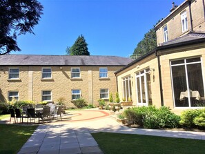 A building with multiple windows and a paved courtyard with outdoor furniture. - Astley Bank Hotel (Darwen)