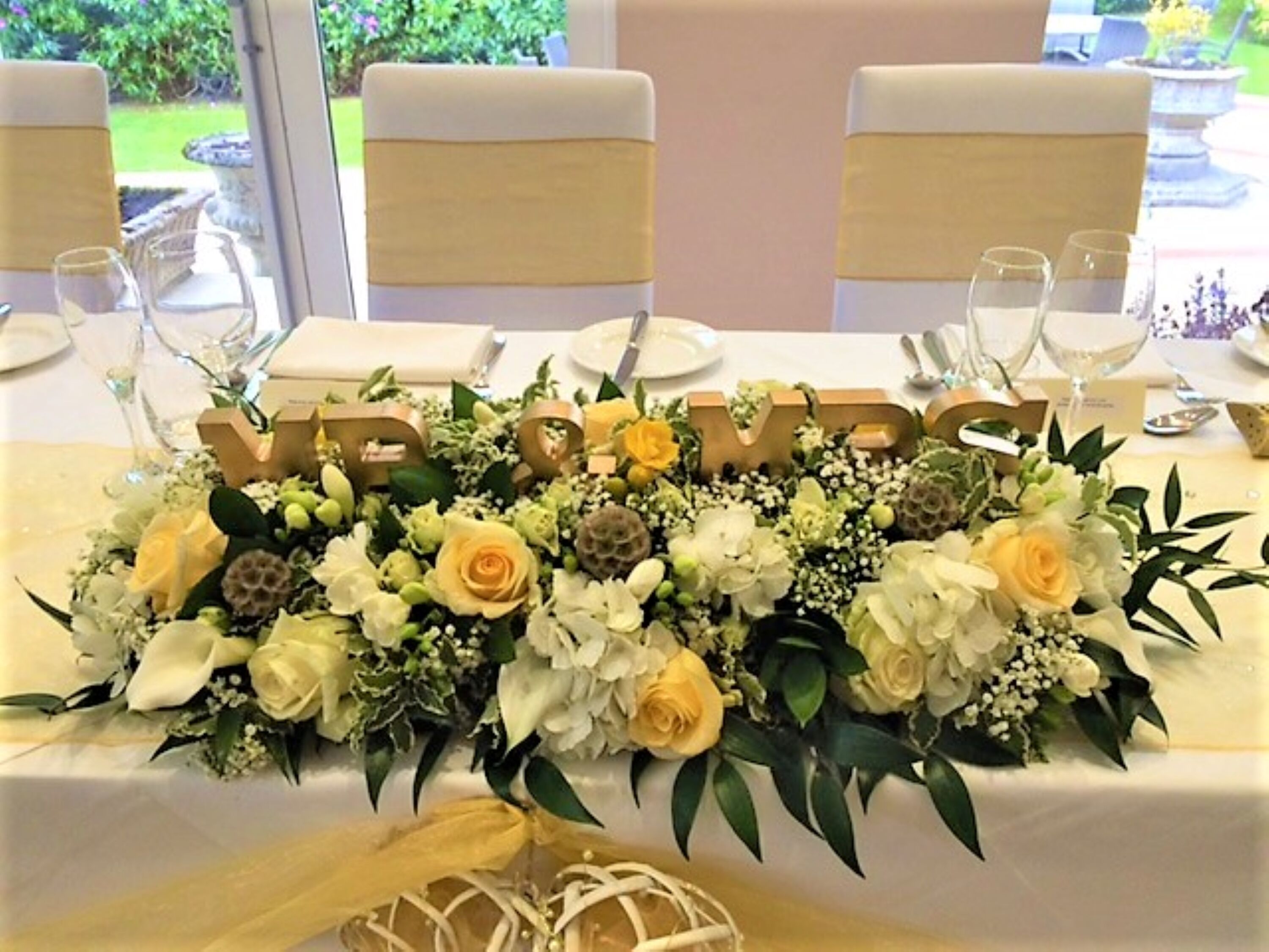 A table with a floral centerpiece and 'LOVE' letters, surrounded by chairs and dining ware.