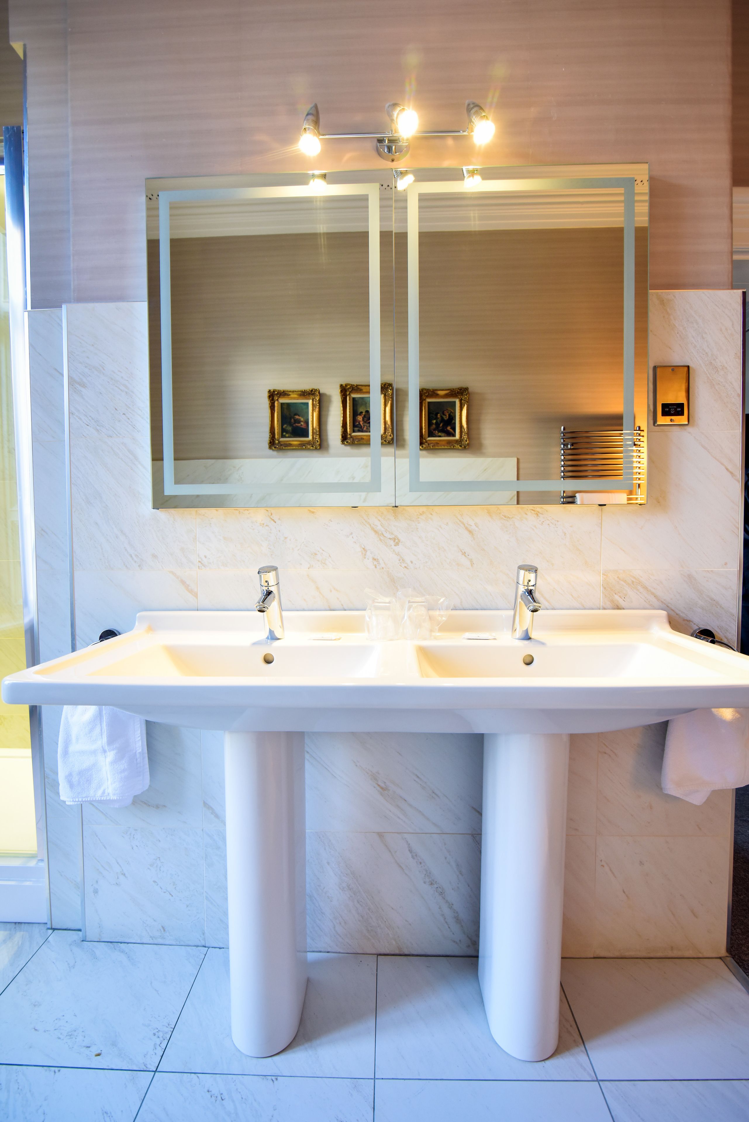 A bathroom with two sinks, a large mirror, and a towel rack.