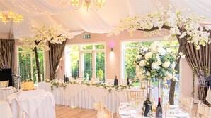 Un salón de banquetes con manteles blancos, centros de mesa florales y candelabros.
