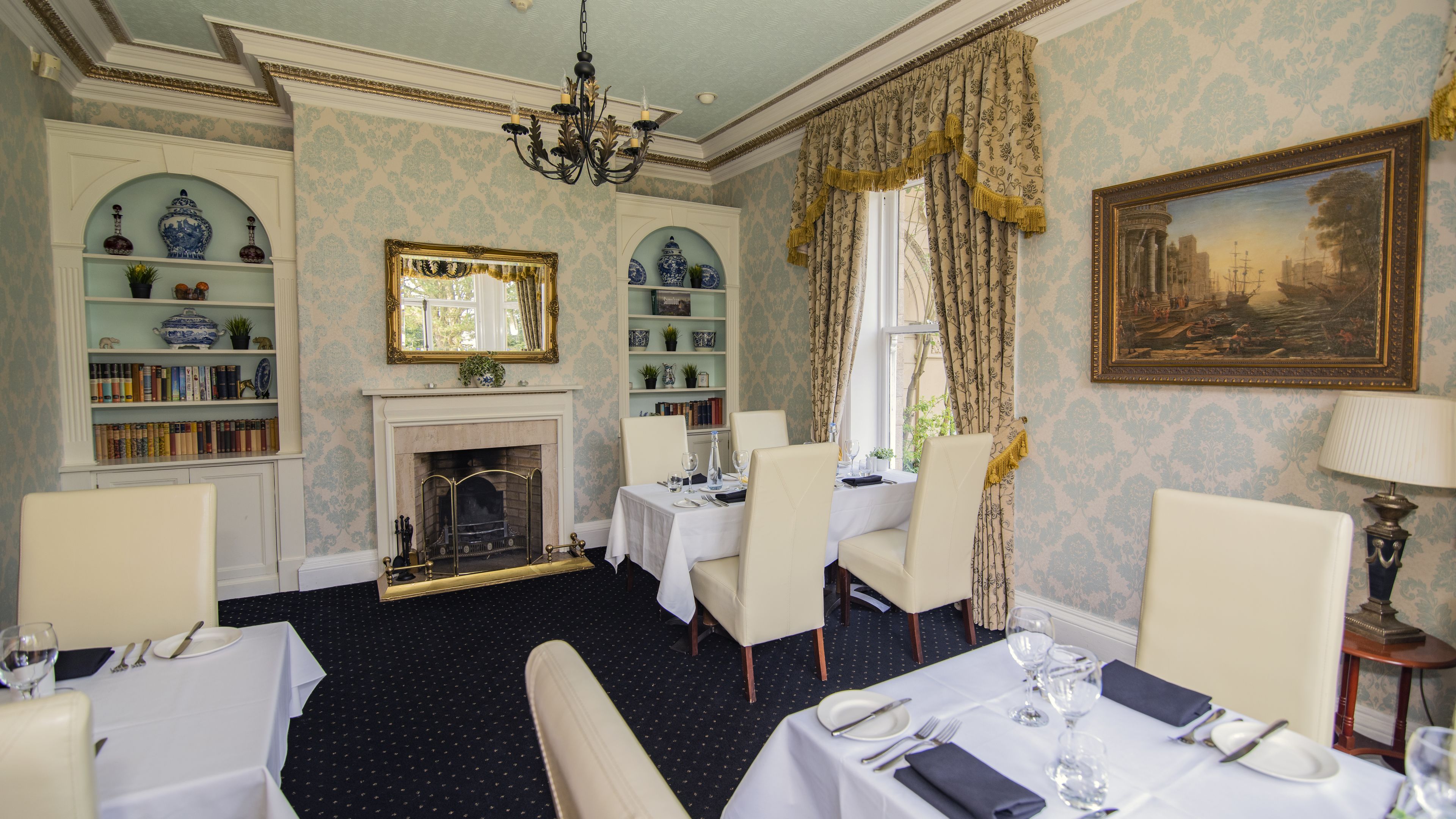 A dining room with a fireplace, bookshelves, and a chandelier.