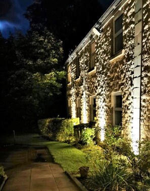 A stone building with illuminated windows and a pathway leading to the entrance. - Astley Bank Hotel (Darwen)