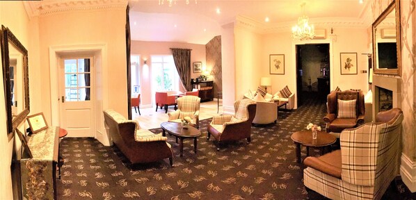 A hotel lobby with a carpeted floor, several armchairs, a sofa, a coffee table, and a fireplace. - Astley Bank Hotel (Darwen)