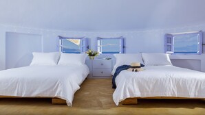 Ein Zimmer mit zwei Betten, einem Nachttisch und Meerblick durch die Fenster.