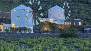 Ein Küstengebäude mit Windmühlen, Steinmauern und einem Weinberg.