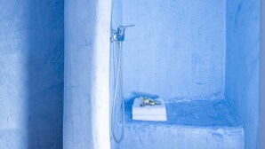 Ein Badezimmer mit blauer Einrichtung, einer Dusche und einer kleinen Stufe mit Handtuch und Flasche.