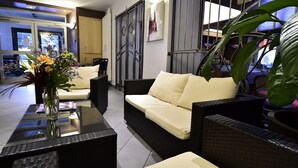 Un salón moderno con sofá, una mesa de centro de vidrio y un jarrón con flores.