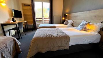 A hotel room with two beds, a desk, a television, and a view of the outdoors.