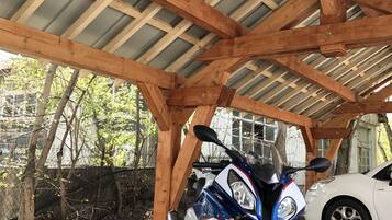 Una motocicleta estacionada bajo una estructura de madera con techo de lámina corrugada.