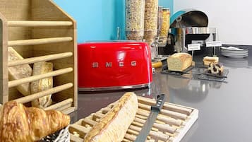 Uma bancada de cozinha com uma torradeira vermelha, pão e uma baguete.