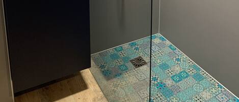 Un baño moderno con cabina de ducha de vidrio, un lavabo blanco y un salpicadero de azulejos.
