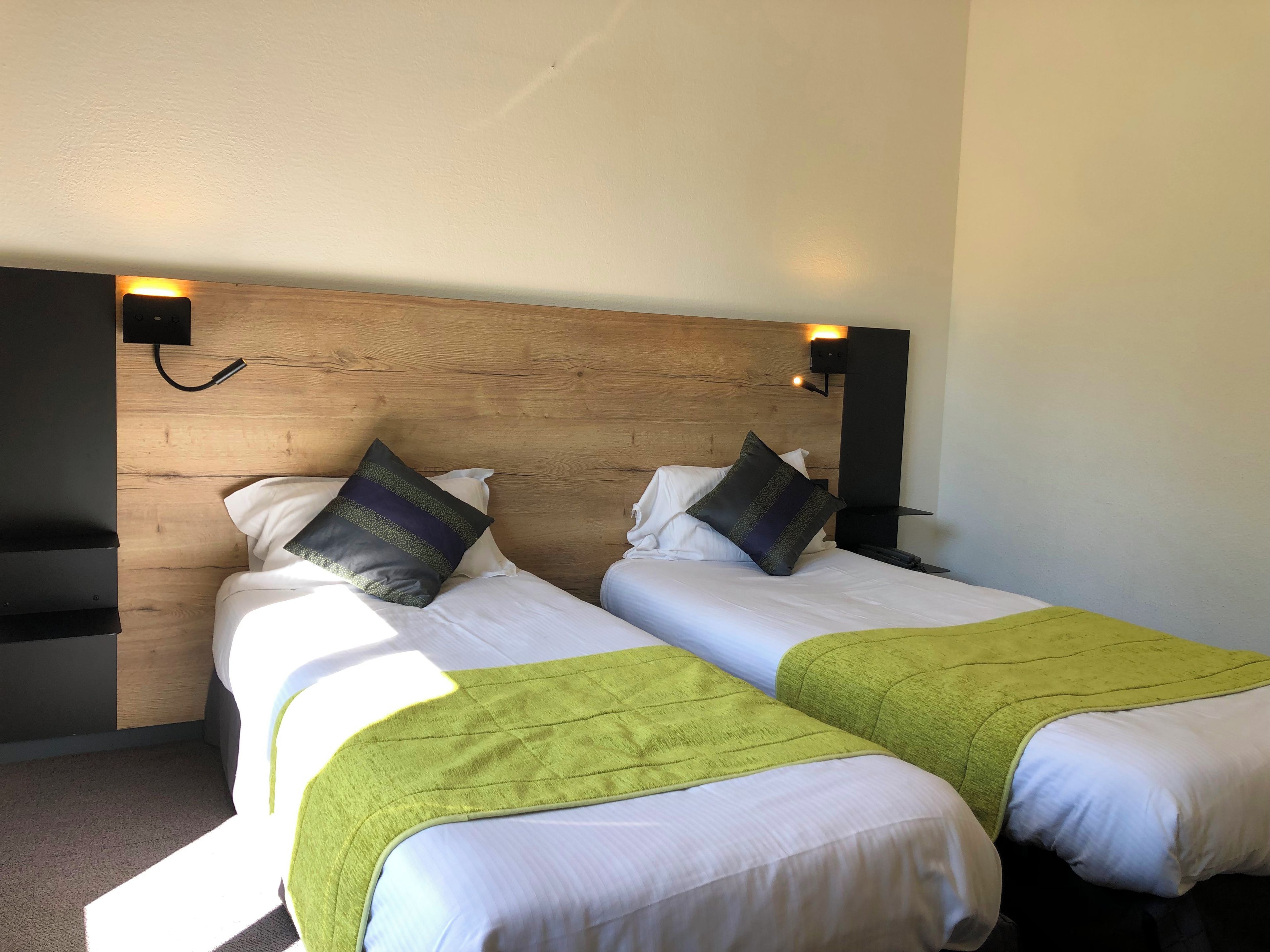 Un lit double avec deux oreillers, une tête de lit en bois et une table de chevet avec une lampe.