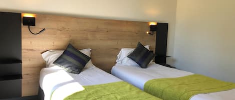 A double bed with two pillows, a wooden headboard, and a bedside table with a lamp.