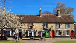 A traditional brick building with a red door, multiple windows, and outdoor seating. - The George and Dragon Inn (Sudbury)