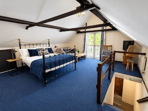 A bedroom with a bed, a desk, a chair, a television, and a balcony. - The George and Dragon Hotel (Sudbury)
