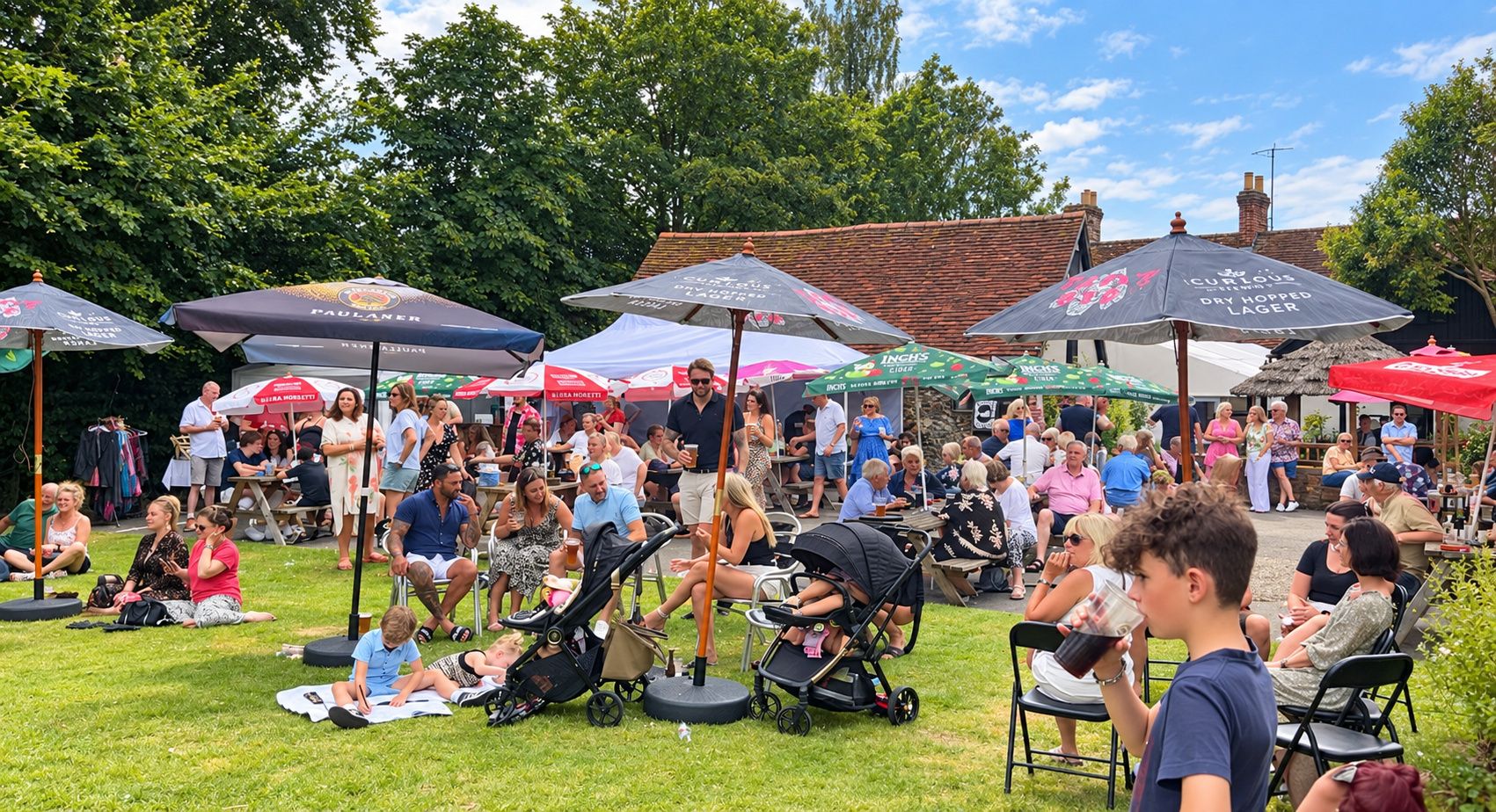 An outdoor gathering with people seated under umbrellas, some with children.